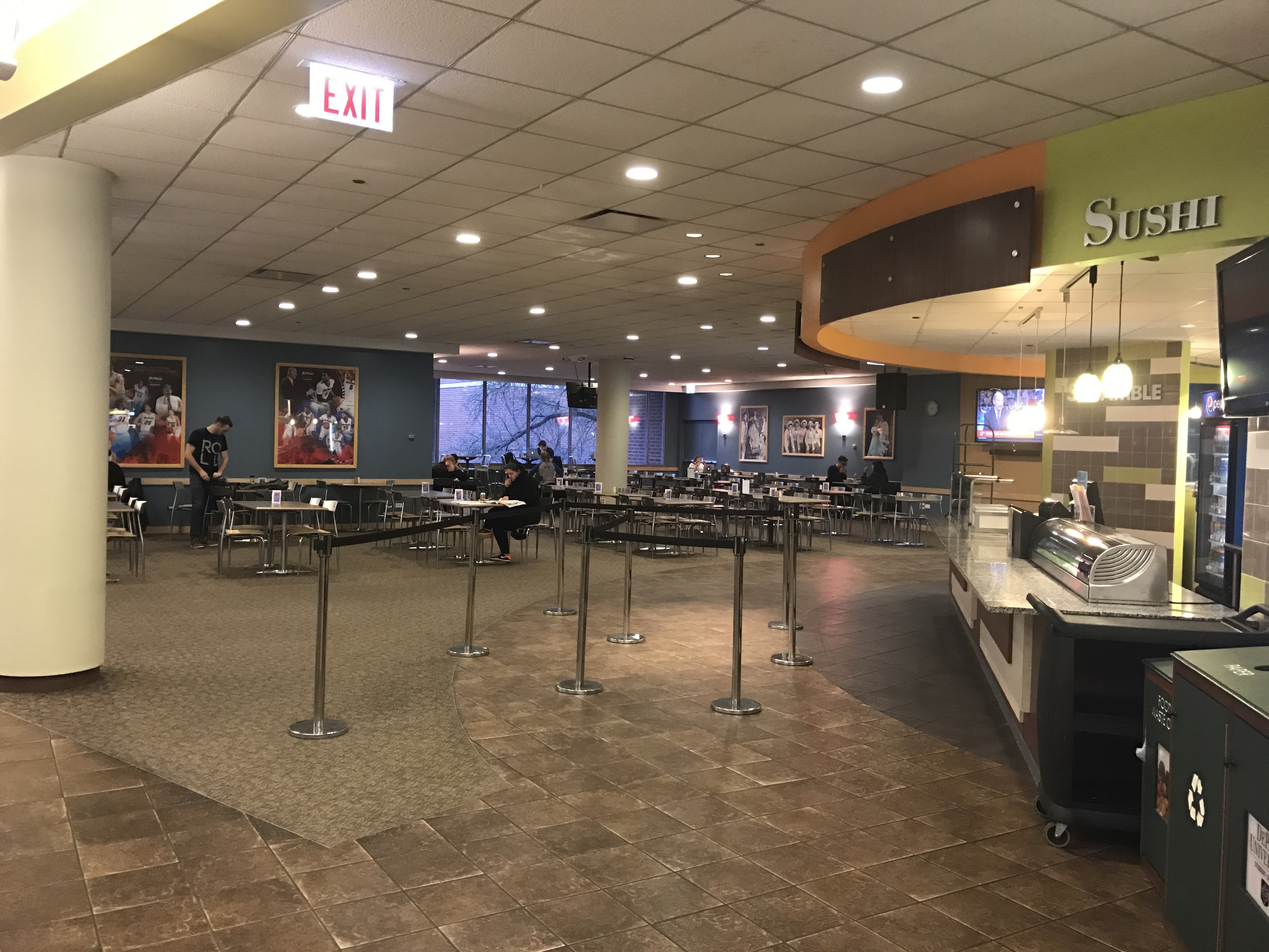 Open area with tables and chairs next to a sushi bar.