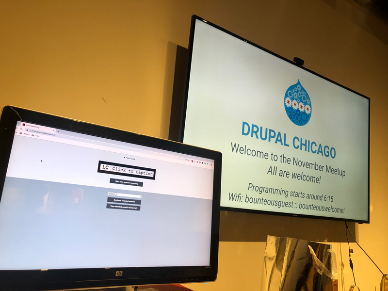 Close up view of a Live Captioning monitor and screen at a Chicago Drupal Meet Up