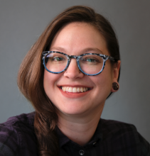 Headshot of Marissa Epstein, a smiling brunette woman wearing glasses and a button-down shirt