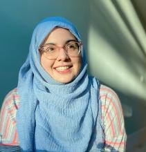 a smiling fatima in her mint green apartment and a sunbeam.