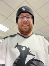 Man wearing glasses wearing a MidCamp hat and a Backdrop CMS hockey jersey