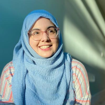 a smiling fatima in her mint green apartment and a sunbeam. 