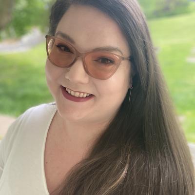 Alanna Burke Headshot. Smiling Brunette with glasses. 